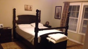 A four-poster bed with a wooden frame, a nightstand with a lamp, and a window with blinds. - motor home (Columbia)