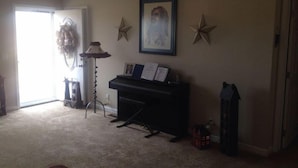A living room with a piano, a wall-mounted star decoration, and a framed picture. - motor home (Columbia)