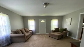 A spacious living room with beige carpet, two beige sofas, and a wooden coffee table. - The Old Farmhouse. (Dry Ridge)