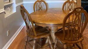 A dining area with a wooden table and four chairs, a decorative wall piece, and a shelf with a sunflower arrangement. - The Old Farmhouse. (Dry Ridge)