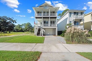 A two-story residential building with a front porch, a garage, and a well-maintained lawn. - Bonito Bliss - Golf Cart Included! 722 Bonito (Fripp Island)