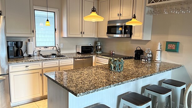 A modern kitchen with granite countertops, stainless steel appliances, and pendant lighting. - Brigantine dream home just steps to the beach! (Brigantine)