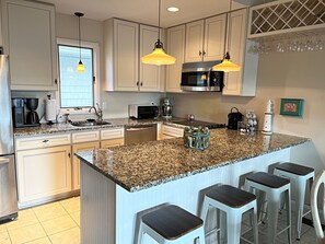A modern kitchen with granite countertops, stainless steel appliances, and pendant lighting. - Brigantine dream home just steps to the beach! (Brigantine)