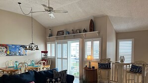 A cozy living room with a dark blue sofa, a wooden coffee table, and a chandelier. - Brigantine dream home just steps to the beach! (Brigantine)