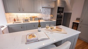 A modern kitchen with grey cabinets, a white countertop, and a built-in oven. - 1 Bridge Syke, Elterwater (Ambleside)