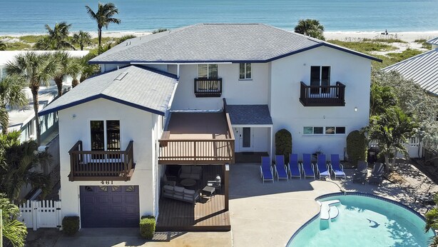 Ein zweistöckiges Haus mit Pool, Balkon und Blick auf den Strand.