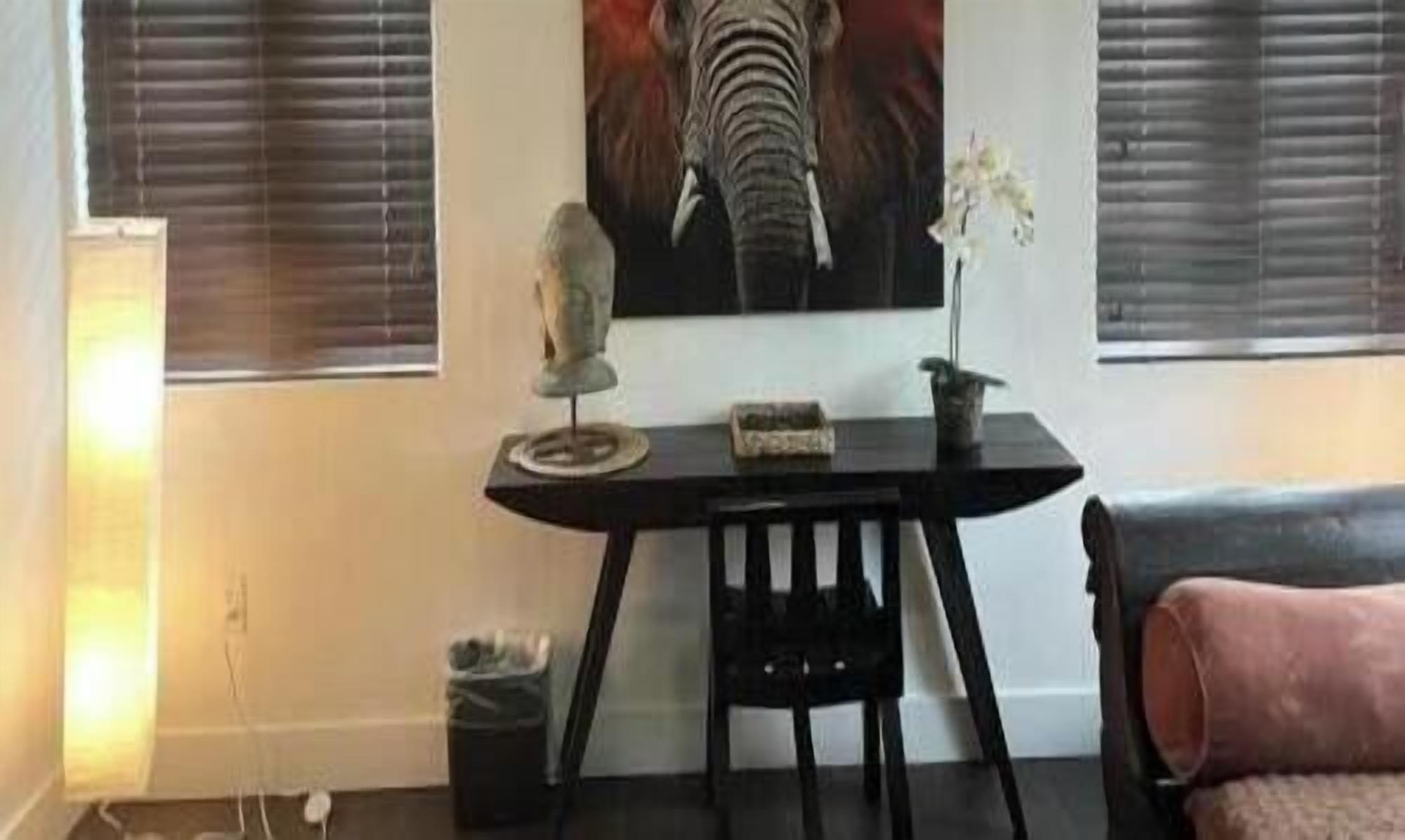 Una habitación con una mesa negra, una pequeña estatua y una planta en maceta.