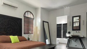 A bedroom with a large bed, a dresser, a mirror, and a window with blinds. - Home Away from Home in Miami Street Parking (Miami)