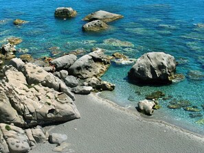 Una costa rocosa con aguas azules cristalinas y grandes rocas.