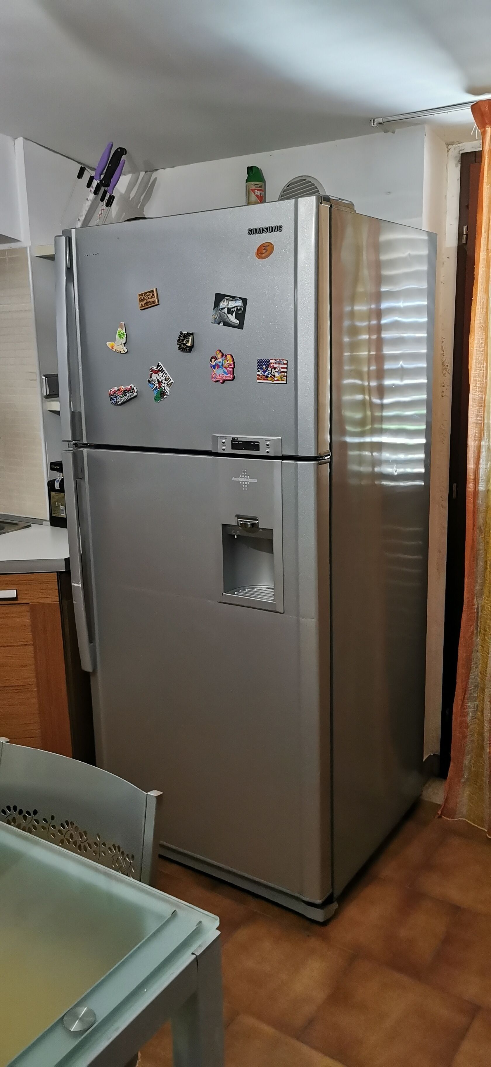 A stainless steel refrigerator with a water dispenser and magnets on the door.