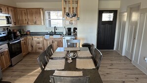 A modern kitchen with wooden cabinets, a built-in oven, and a dining area with a wooden table and chairs. - Outdoorsman Paradise (Wolf Lake)