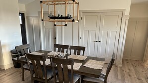 A dining area with a wooden table and chairs, a hanging light fixture, and white doors in the background. - Outdoorsman Paradise (Wolf Lake)