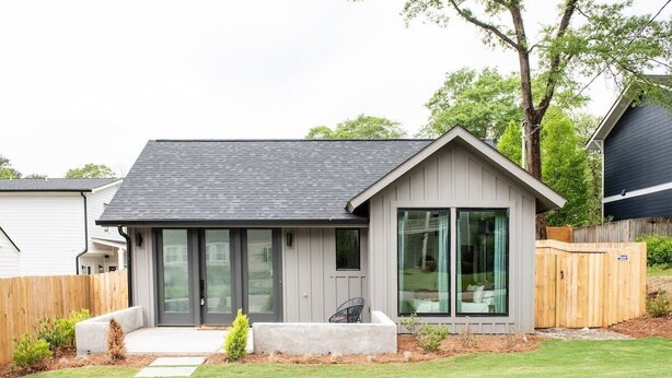 A modern house with a grey exterior, large sliding glass doors, and a small front porch. - Dapper Dan (Atlanta)