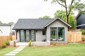 A modern house with a grey exterior, large sliding glass doors, and a small front porch. - Dapper Dan (Atlanta)