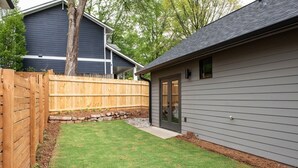 A backyard with a wooden fence, a small shed, and a tree. - Dapper Dan (Atlanta)