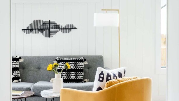 A modern living room with a sofa, a yellow armchair, a round wall decoration, and a patterned rug. - Dapper Dan (Atlanta)