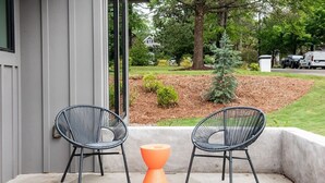 A patio with two black wire mesh chairs and an orange stool. - Dapper Dan (Atlanta)
