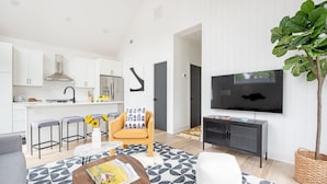 A modern living space with a kitchen, dining area, and a TV mounted on the wall. - Dapper Dan (Atlanta)