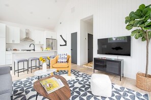 A modern living space with a kitchen, dining area, and a TV mounted on the wall. - Dapper Dan (Atlanta)