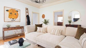 A living room with a sofa, a coffee table with a book, a vase, and a painting of a leopard.