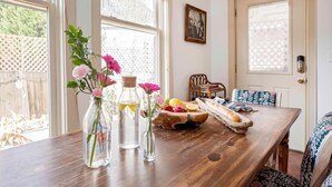 A dining table with a wooden bench, a vase with flowers, and a fruit basket.