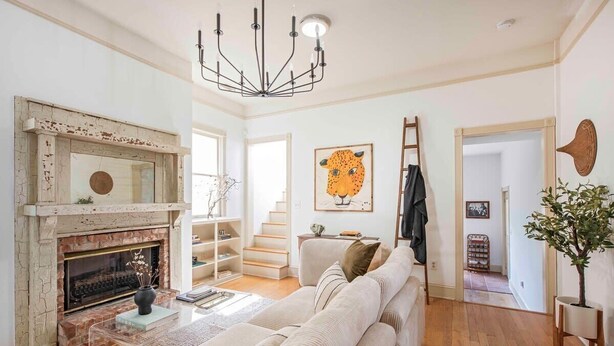 A spacious living room with a fireplace, a large sofa, and a chandelier.