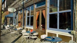An outdoor cafe with tables and chairs, large windows, and a sign for Carroll St. Cafe.