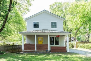 A two-story house with a porch, a yellow door, and a small garden area. - Cherry Cola (Atlanta)