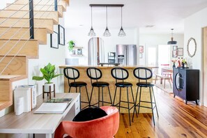 Una cocina moderna con una isla central, taburetes de bar y una escalera.