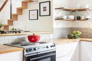 Une cuisine équipée d’une cuisinière, d’un four et d’étagères en bois.