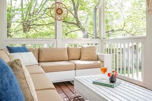 Ein gemütlicher Sitzbereich mit einem beigen Sofa, einem weißen Couchtisch, einem Buch und einem Getränk.