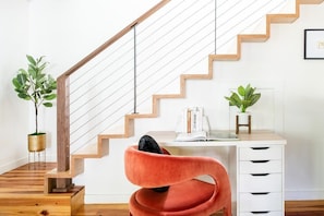 Eine Treppe mit Holzdielen und Metallgeländer, ein Schreibtisch mit Schubladen und zwei Zimmerpflanzen.