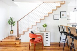 Une cuisine moderne avec un escalier en bois, un bureau et des tabourets de bar.