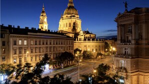 A historic building with classical architecture, including a prominent dome and towers, surrounded by other classical buildings and a busy street at night. - Venus Apartments - Italian Stylish (Budapest)