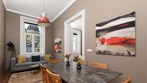 A dining area with a wooden table, chairs, and a view of a cityscape through a window. - Venus Apartments - Italian Stylish (Budapest)