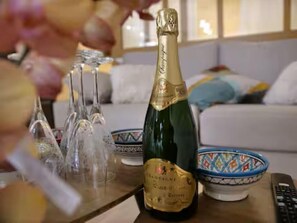 Una botella de champán sobre una mesa con copas y un bol.