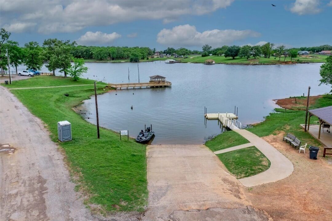 Un lago con un muelle, una zona de estar techada y un sendero que lleva al agua.