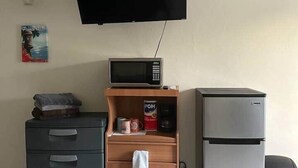 A small kitchenette with a microwave, a refrigerator, a wooden cabinet with a towel hanging, and a television mounted on the wall. - Cayo Vieques at Almendro Guest House (Lajas)