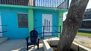 A building with a blue exterior, a white door, and a black chair in front. - Cayo Vieques at Almendro Guest House (Lajas)