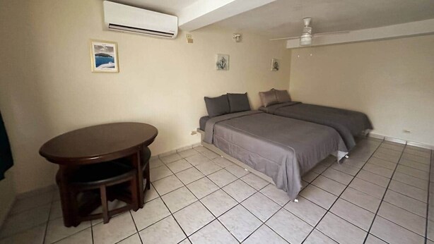 A small, clean room with a bed, a table, and an air conditioning unit. - Cayo Vieques at Almendro Guest House (Lajas)