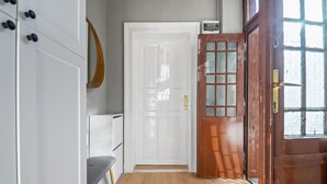 A hallway with a white door, a wooden door with glass panels, and a bench. - Venus Apartments - Akacfa street I (Budapest)