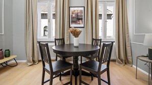 A dining area with a round table, six chairs, a vase with dried flowers, and a framed picture on the wall. - Venus Apartments - Akacfa street I (Budapest)