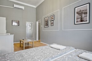 A modern bedroom with a patterned bedspread, a bedside table, a mirror, and framed pictures on the wall. - Venus Apartments - Akacfa street I (Budapest)
