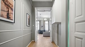 A hallway with framed artwork on the walls, a bench, and a dining area in the distance. - Venus Apartments - Akacfa street I (Budapest)