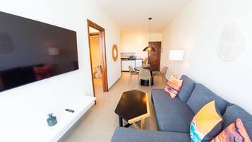 A modern living room with a flat-screen TV, grey sofa, and a small table.