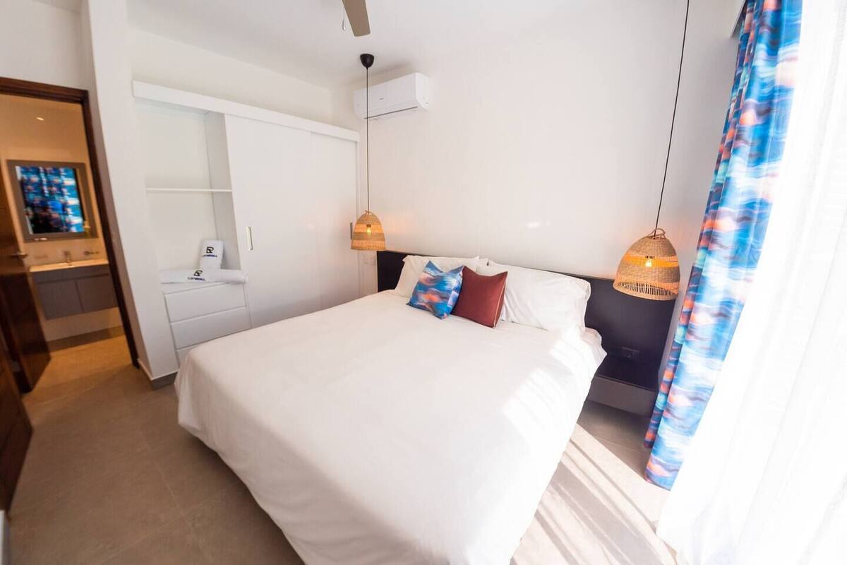 A hotel room with a large bed, a wardrobe, a desk, and a television.