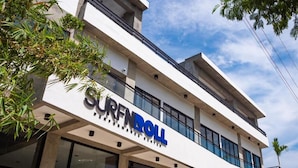 A building with the sign "SURF DOLL PERFORMANCE CENTER" indicating a surf-related facility. - Surf N Roll Performance Center (Cabarete)