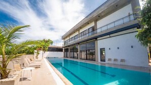 A modern building with a swimming pool, lounge chairs, and a clear sky. - Surf N Roll Performance Center (Cabarete)