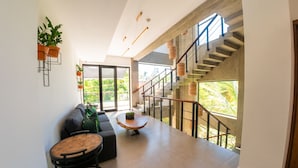 A spacious living area with a staircase, a sofa, a coffee table, and potted plants. - Surf N Roll Performance Center (Cabarete)