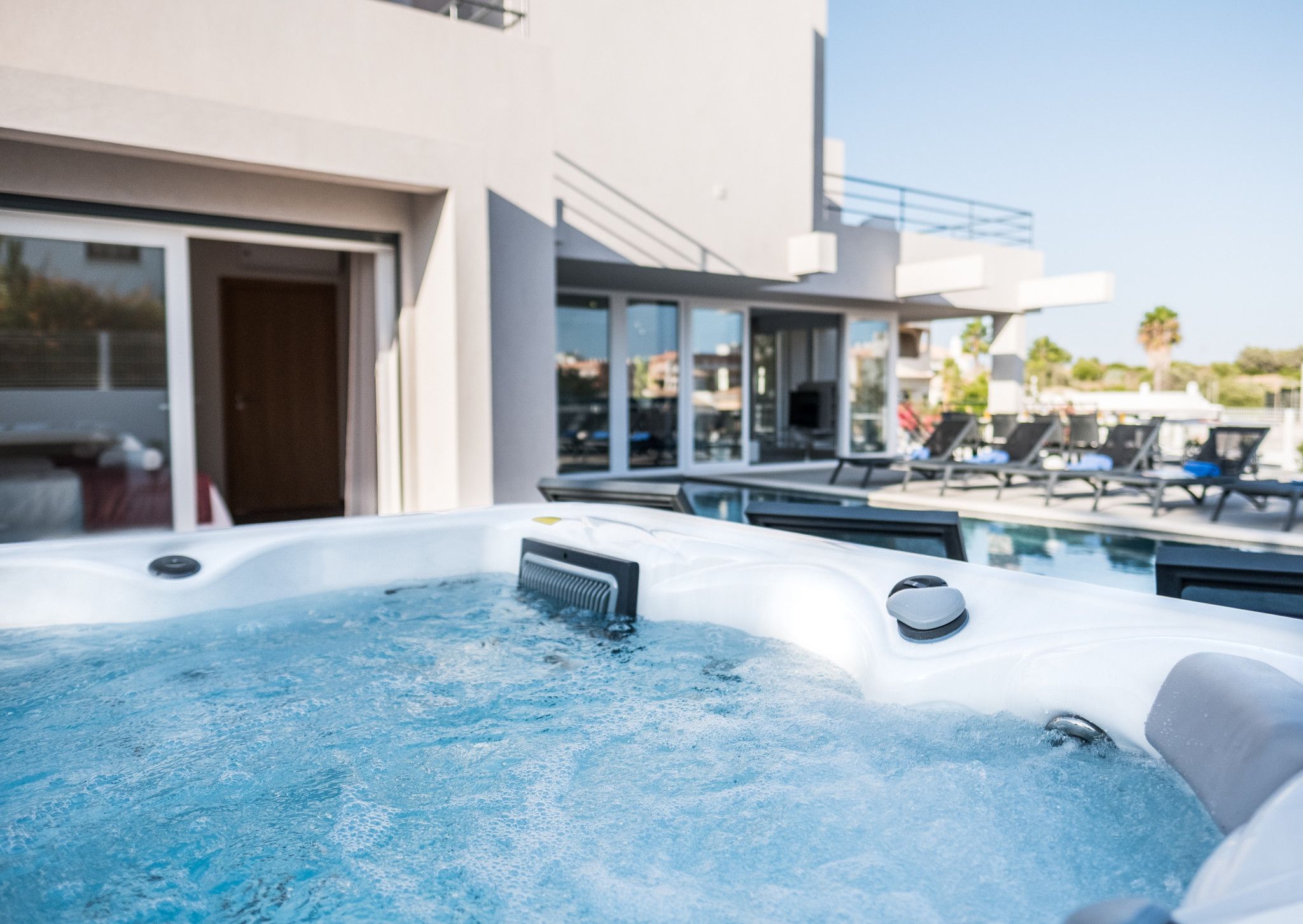 A modern outdoor hot tub area with lounge chairs and a poolside setting.